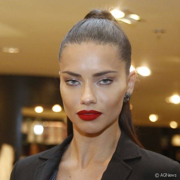 Em evento de lançamento de marca de roupa, Adriana Lima deu destaque à boca com um batom vermelho matte de tom bem intenso